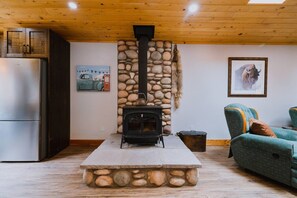 Ein gemütliches Wohnzimmer mit Kamin, einer Couch und einem Kühlschrank.