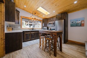 Eine Küche mit Holzausstattung, einer zentralen Kochinsel mit Sitzgelegenheiten, einer Mikrowelle und einem Kühlschrank.