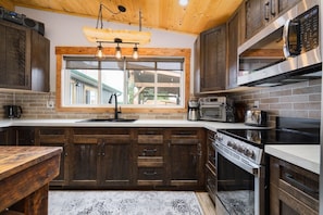 A kitchen with wooden cabinets, a built-in oven, a microwave, and a coffee maker. - The Old West Cabin Steps from the Lake (Sylvan Lake)