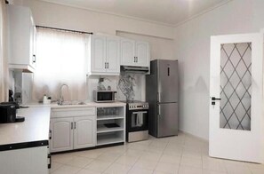 A kitchen with white cabinets, a microwave, a stove, and a refrigerator. - Spacious 2-Bedroom Apartment with Balcony Near Glyfada Center & Beach (Glyfada)