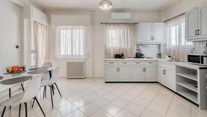 A modern kitchen with white cabinetry, a dining table with chairs, and a built-in oven.