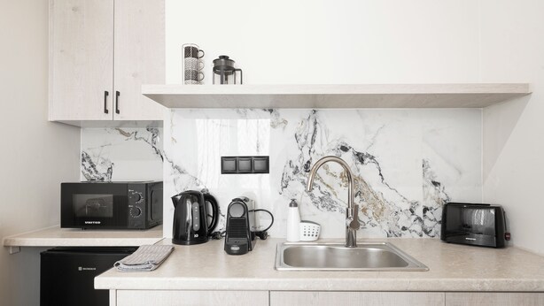 Cocina moderna con microondas, cafetera, tostadora y lavamanos.