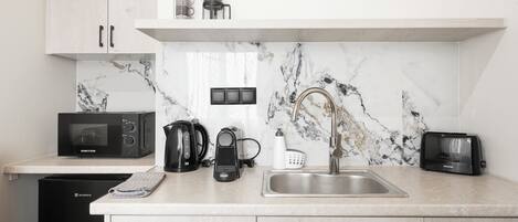 A modern kitchen with a microwave, coffee maker, toaster, and a sink.