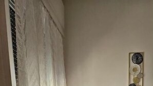 Una habitación con una mesa y sillas, una ventana con cortinas y un adorno en la pared.