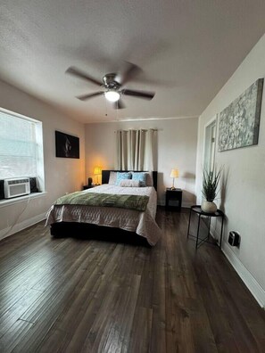 A bedroom with a bed, ceiling fan, bedside lamps, a potted plant, and a window with blinds. - Restful Retreat w/Smart TV & Free Parking near NRG (Houston)