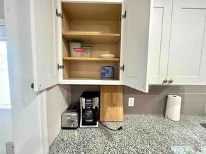 Eine Küche mit integriertem Kaffeeautomaten, einem Toaster und einem Regal mit Behältern.