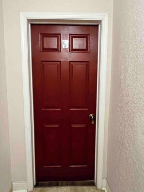 A closed wooden door with a brass doorknob, a white frame, and a small rectangular window above the door. - Restful Retreat w/Smart TV & Free Parking near NRG (Houston)
