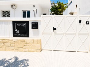 A gated entrance with a sign for 'GLYFADA STAY' and a website address. - Spacious 3-Bedroom Apartment with Balcony Near Glyfada Center & Beach (Glyfada)