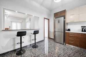 Eine moderne Küche mit einem Kühlschrank, einer Kaffeemaschine und zwei Barhocker.