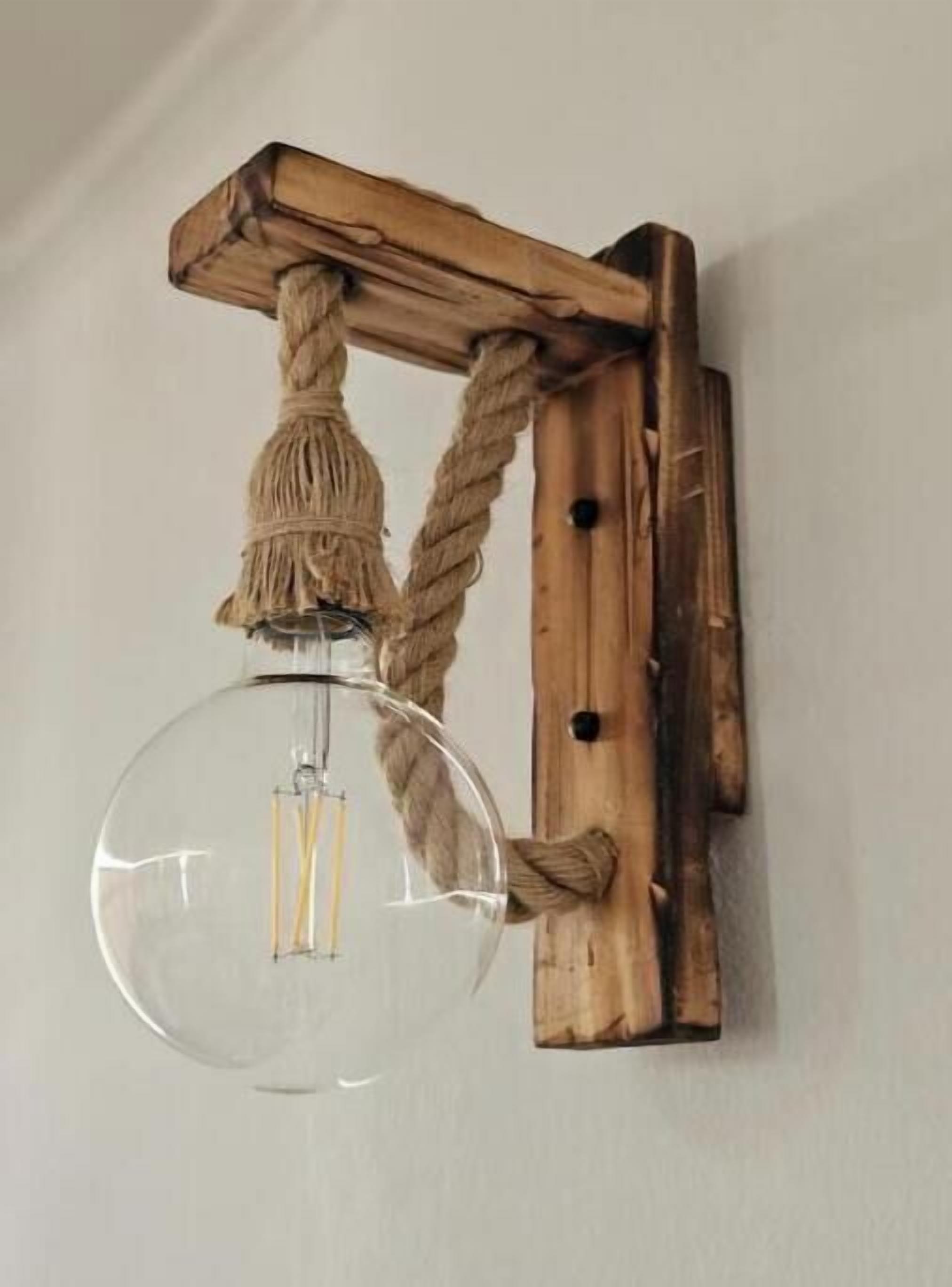 Un luminaire mural doté d’un abat-jour en verre transparent et d’un socle en bois.