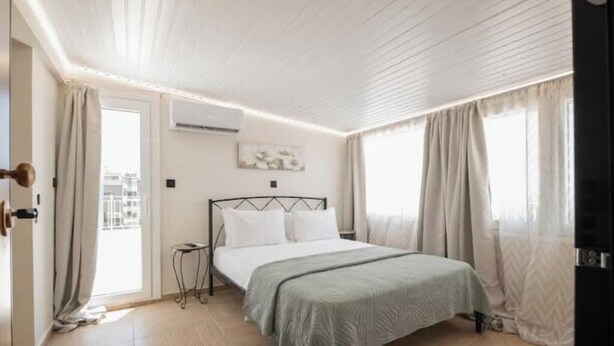 Une chambre à coucher comprenant un lit, une table de chevet, une fenêtre avec des rideaux et un appareil de climatisation.