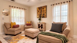 A living room with a sofa set, ottoman, and a small cabinet. - Houston Stay | Private Suite + Workspace (Houston)