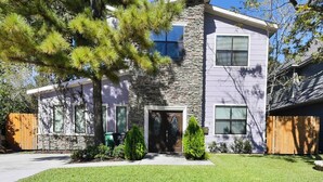 A two-story house with a stone facade, a front door, and a small front yard with a tree and shrubs. - Near NRG Houston Stay - Patio + Free Parking (Houston)