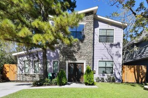 A two-story house with a stone facade, a front door, and a small front yard with a tree and shrubs. - Near NRG Houston Stay - Patio + Free Parking (Houston)