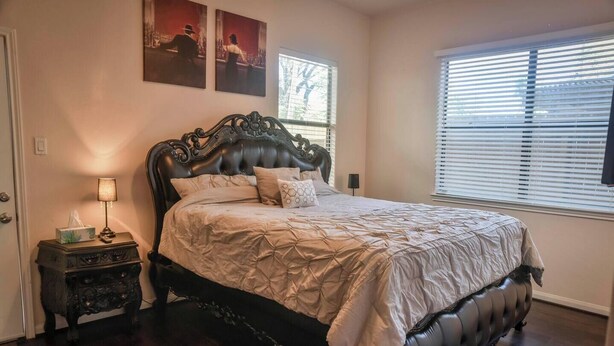 A bedroom with a large bed, a nightstand, a lamp, and artwork on the wall. - Near NRG Houston Stay - Patio + Free Parking (Houston)