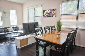 A living room with a sofa, a TV, a dining table with chairs, and a plant. - Near NRG Houston Stay | Patio + Free Parking (Houston)