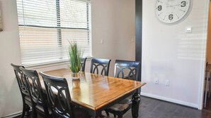 A dining area with a wooden table and black chairs, a potted plant, and a wall clock. - Near NRG Houston Stay - Patio + Free Parking (Houston)