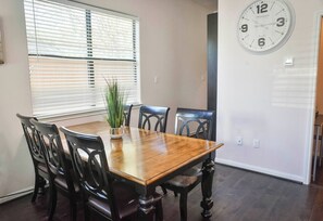 A dining area with a wooden table and black chairs, a potted plant, and a wall clock. - Near NRG Houston Stay - Patio + Free Parking (Houston)