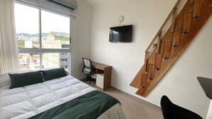 A bedroom with a bed, a desk, a chair, a TV, and a staircase. - VIP Nomad Nest in New PH With Air C, Kitchen, Steps to Metroplus (Medellín)