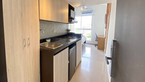 A modern kitchen with wooden cabinets, a black countertop, and a built-in stove. - VIP Nomad Nest in New PH With Air C, Kitchen, Steps to Metroplus (Medellín)