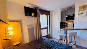 Une petite chambre comprenant un lit, un bureau et une kitchenette.