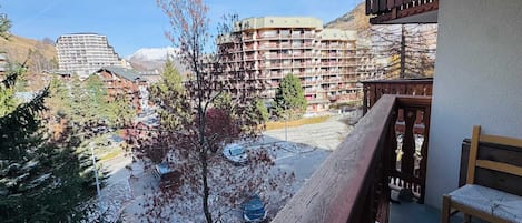 A balcony with a view of a ski resort, including buildings and trees.