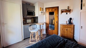 Une pièce compacte comprenant un coin cuisine, un lit, une petite table et une chaise.