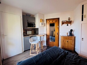 A compact room with a kitchenette, a bed, a small table, and a chair. - Studio Apartment Rental for 2 People in Les 2 Alpes (Les Deux Alpes)