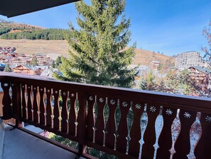 A balcony with a view of a town, including buildings and a mountain. - Studio Apartment Rental for 2 People in Les 2 Alpes (Les Deux Alpes)