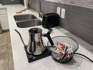 Een keuken met een roestvrijstalen waterkoker, een broodrooster en een mand met tijdschriften.