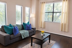 Ein Wohnzimmer mit einer Couch, Kissen, einem Couchtisch und einer Lampe.