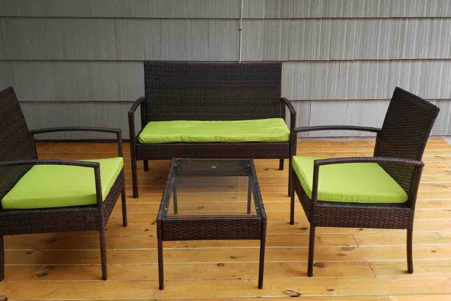 A set of wicker furniture with green cushions on a wooden floor.