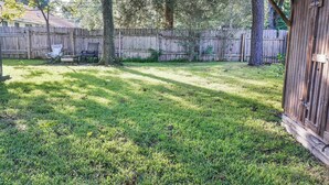 Ein Garten mit Holzzaun, einem Baum und einem Gartenhaus.