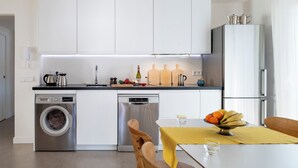 Eine moderne Küche mit Waschmaschine, Geschirrspüler und einem Essbereich mit Tisch für zwei Personen.