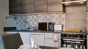 A modern kitchen with a patterned backsplash, a toaster, a microwave, and a stove. - Stunning 2BDR 2Bath Salford Apartment with Parking (Greater Manchester)