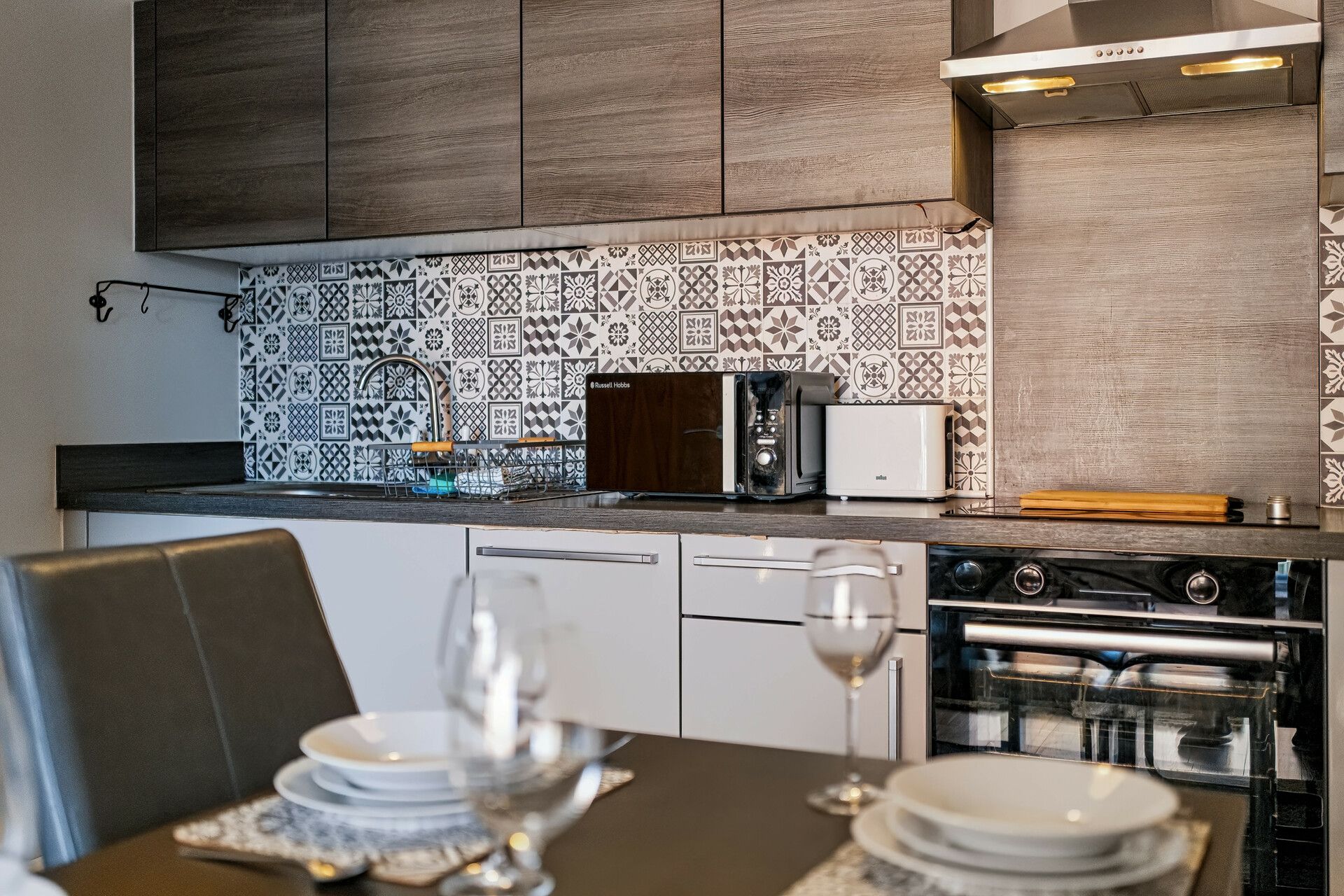 Una cocina moderna con un salpicadero decorativo, un tostador, un microondas y una estufa.
