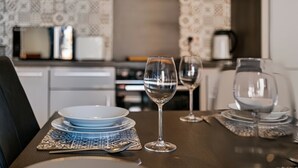 A dining table with plates, glasses, and cutlery, set in a room with patterned wallpaper and a kitchen in the background. - Stunning 2BDR 2Bath Salford Apartment with Parking (Greater Manchester)