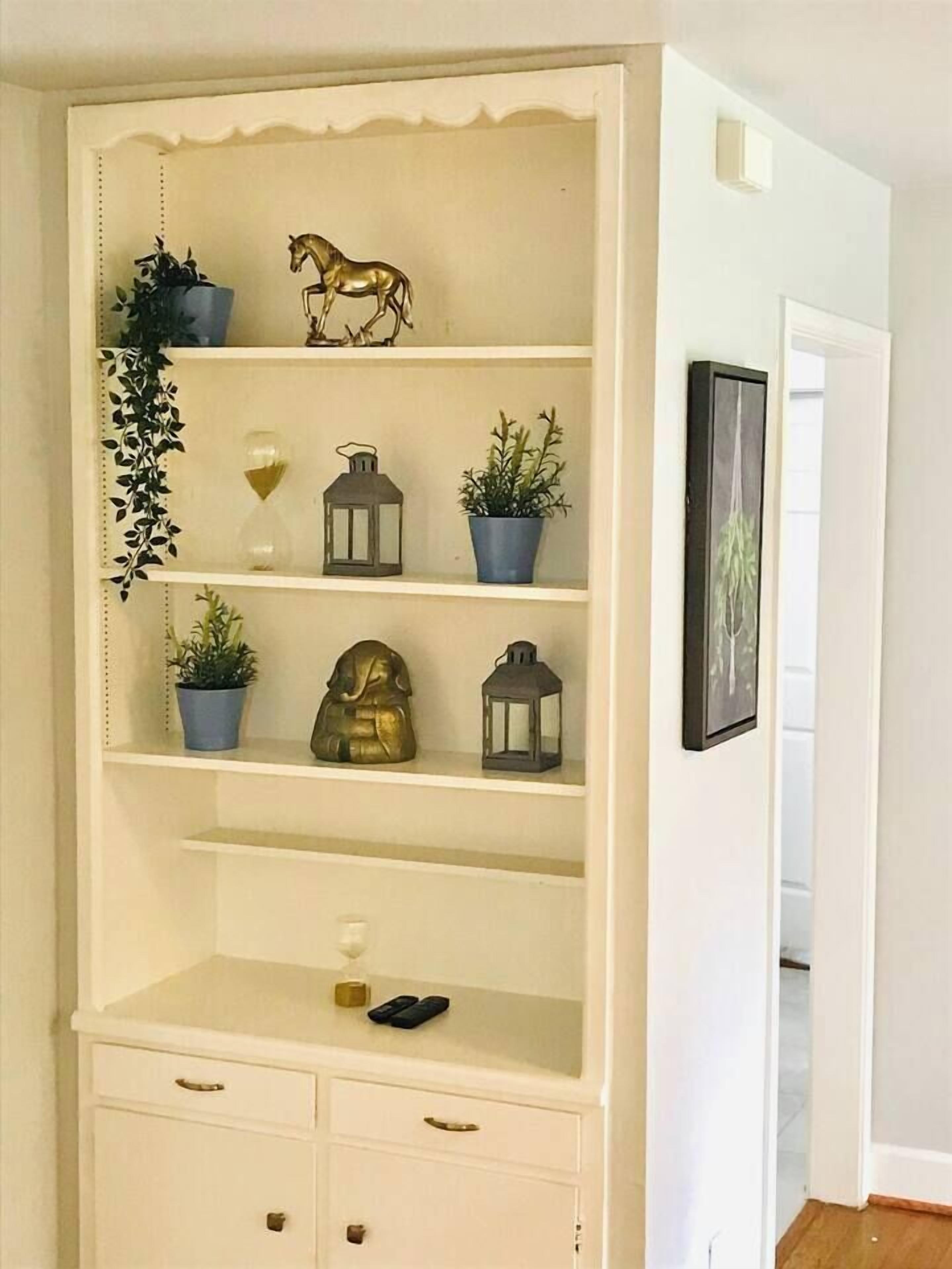 A white shelving unit with decorative items, a small statue, and a lantern.