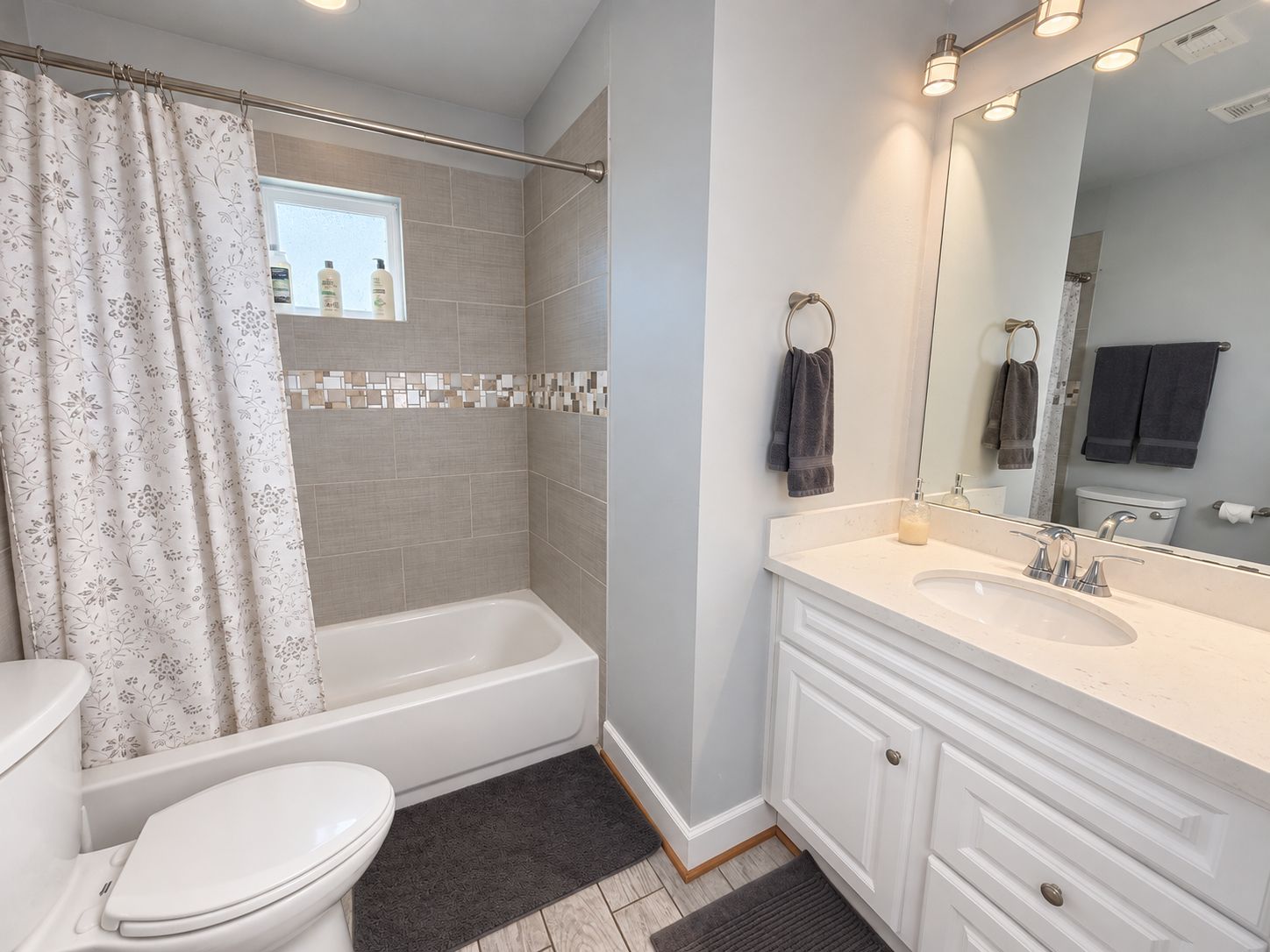A bathroom with a bathtub, toilet, and vanity with a mirror.