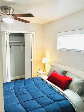 A bedroom with a bed, a nightstand, a lamp, a ceiling fan, and a closet. - Family-Friendly Houston Stay Near NRG Stadium (Houston)