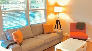 Een zithoek met een bank, salontafel, vloerlamp en fauteuil.