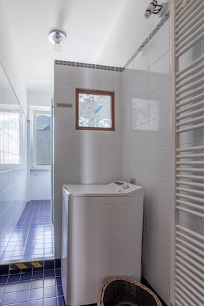 A laundry room with a white washing machine, a window with a view of a mountainous landscape, and a tiled floor. - Holiday Home 'La Quiete' with Wi-Fi (Arizzano)
