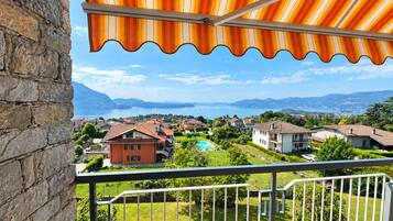 Un balcón con vistas a una zona residencial, una piscina y montañas a lo lejos.