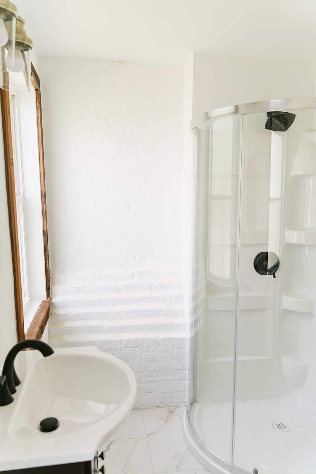 Une salle de bain avec un lavabo blanc, un miroir et une douche à parois de verre.
