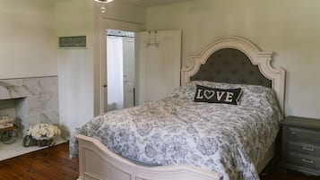 A bedroom with a bed, a nightstand, a dresser, a door, and a chandelier.