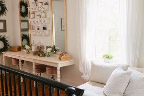 A room with a white desk, a mirror, and a window with curtains.