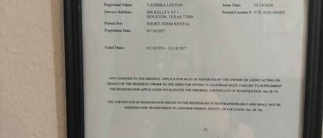 A framed short-term rental certificate of registration for Yadhira Leeton, dated 02/18/2026, with a permit/license number STR-2026-000892.