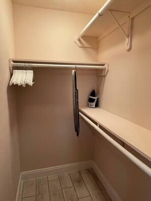 A small, enclosed walk-in closet with a metal rod rack, a white shelf, and a white basket. - Central Houston Base near Heights, Midtown & DTWN (Houston)