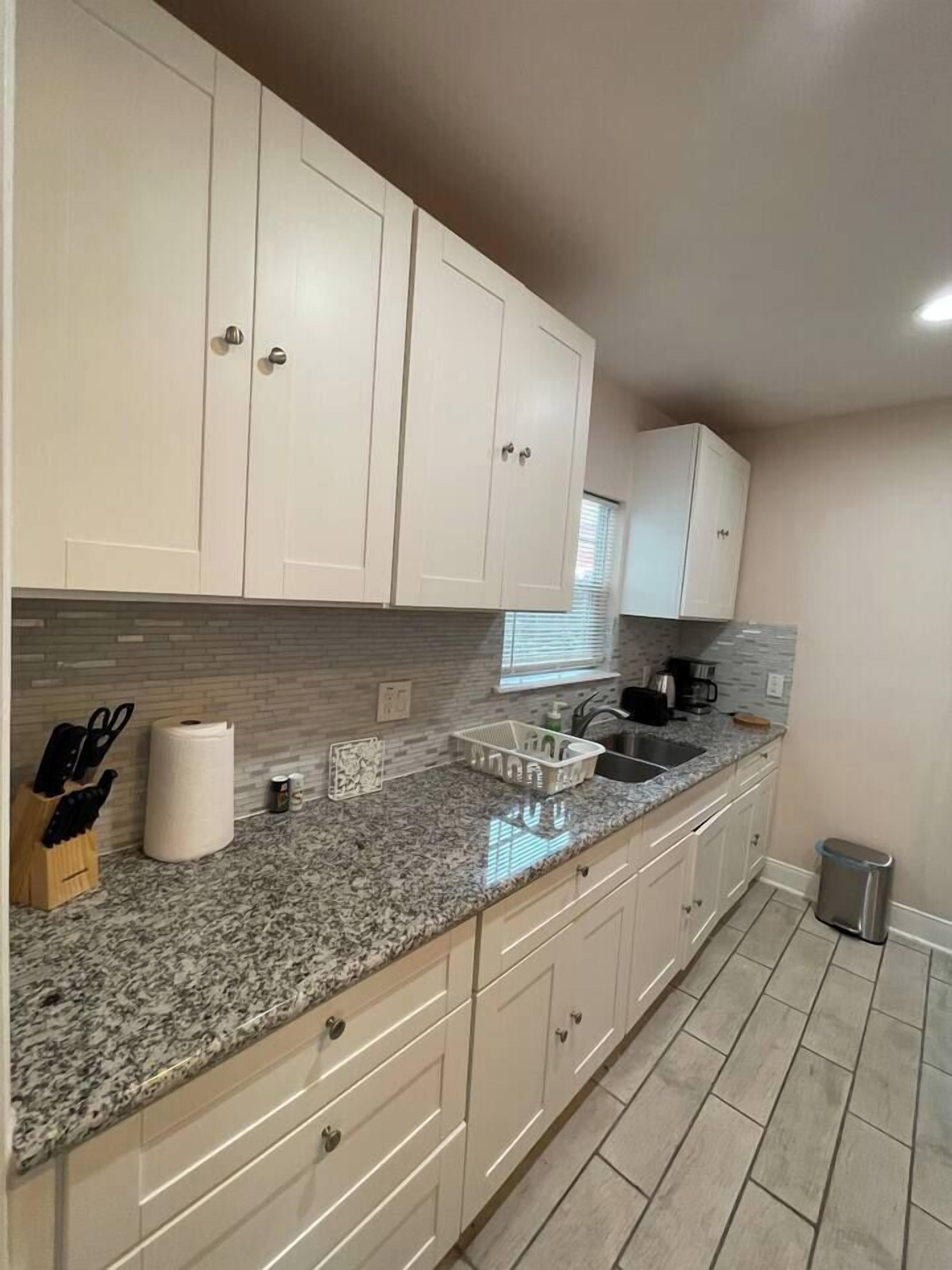 A kitchen with white cabinets, a granite countertop, and a stainless steel sink.