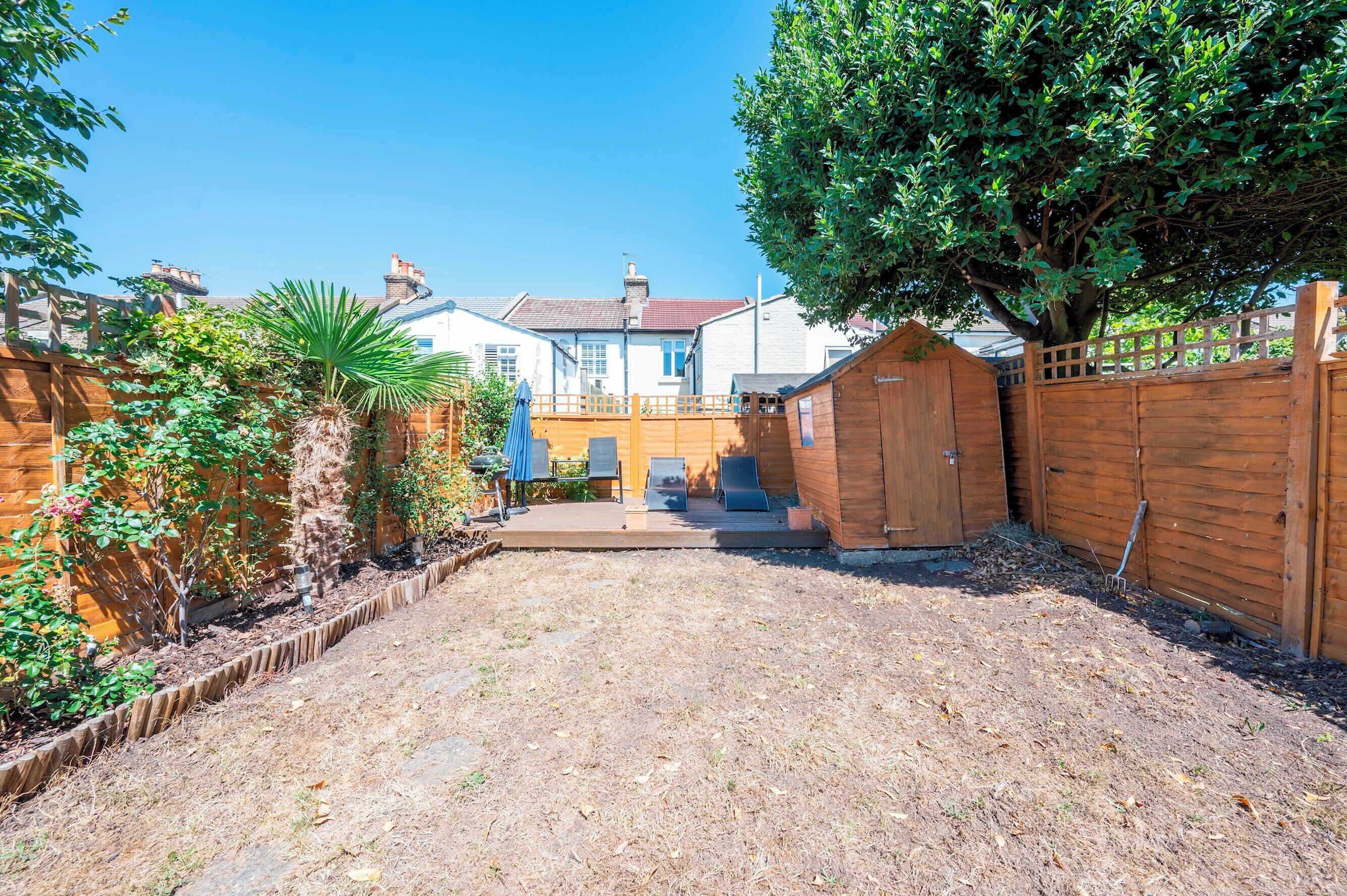 A backyard with a wooden fence, a tree, and a small shed.